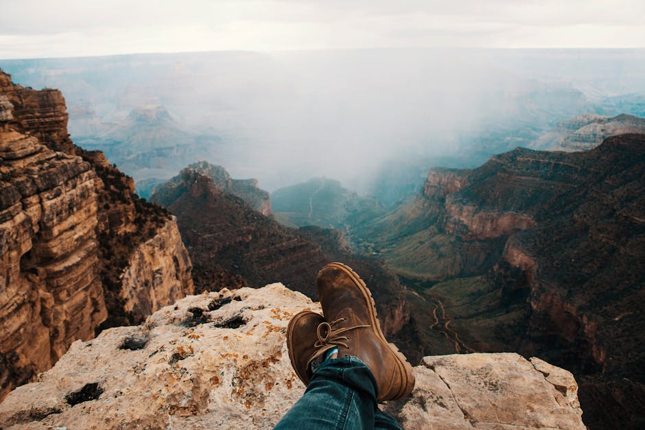 Brown boots on a rocky perch overlooking the vast Grand Canyon landscape.