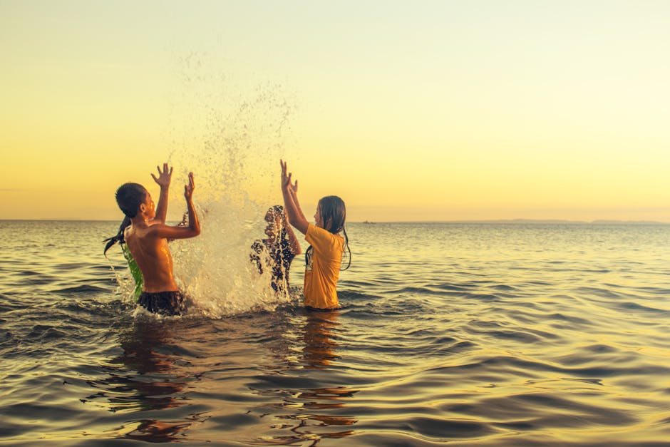 Children splash and play in the ocean at sunset in Donsol, Philippines, capturing a joyful and carefree moment.